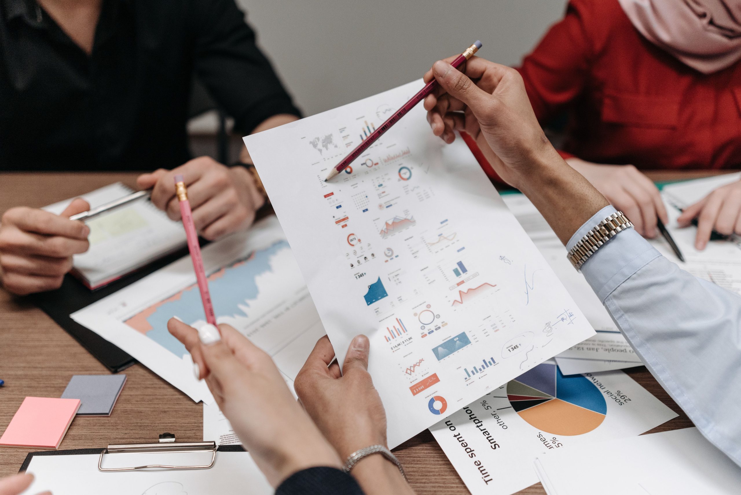 Colleagues reviewing business reports and charts together during a meeting, illustrating clear and accountable decision-making.