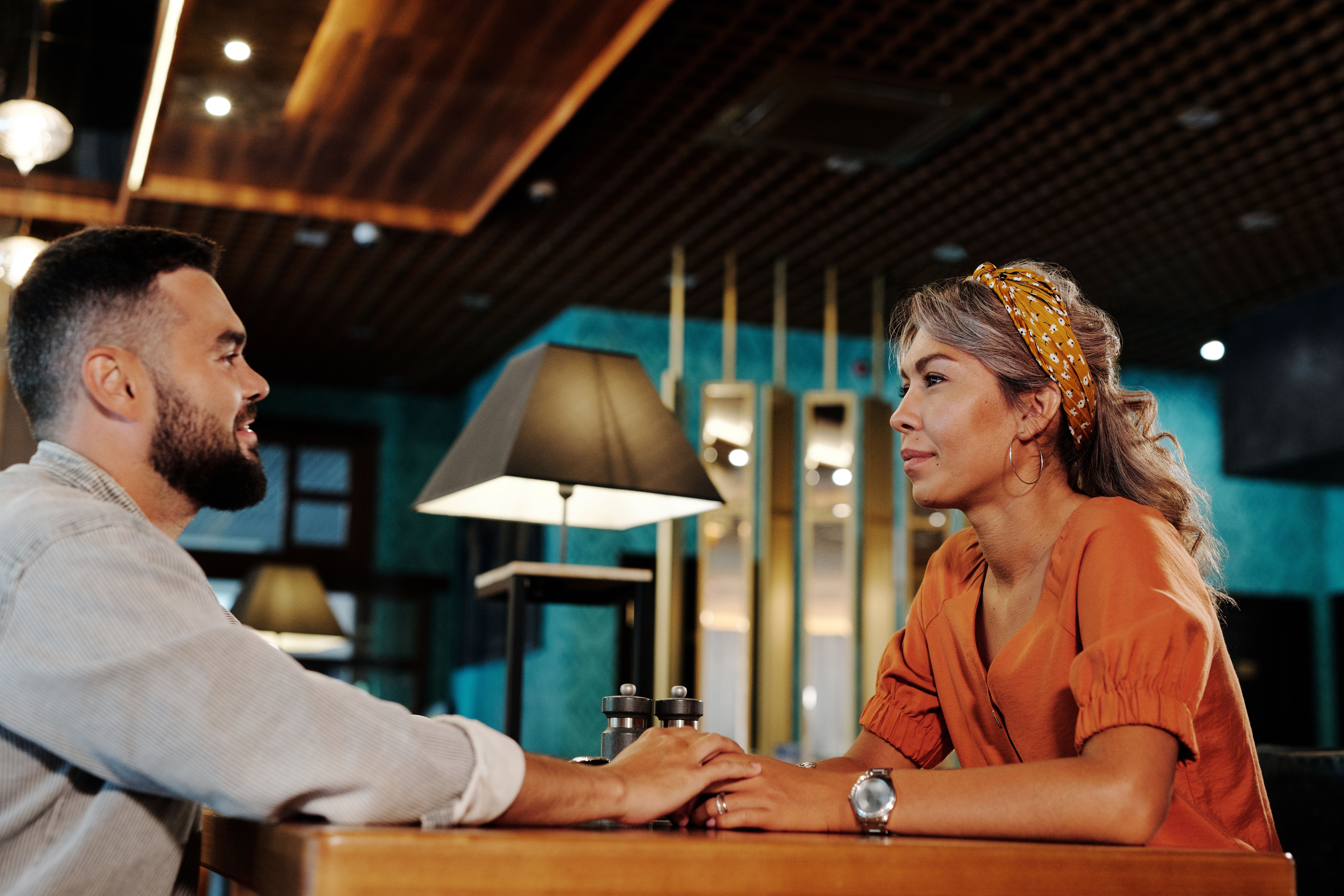 Couple holding hands and talking over coffee, illustrating open communication in a relationship.
